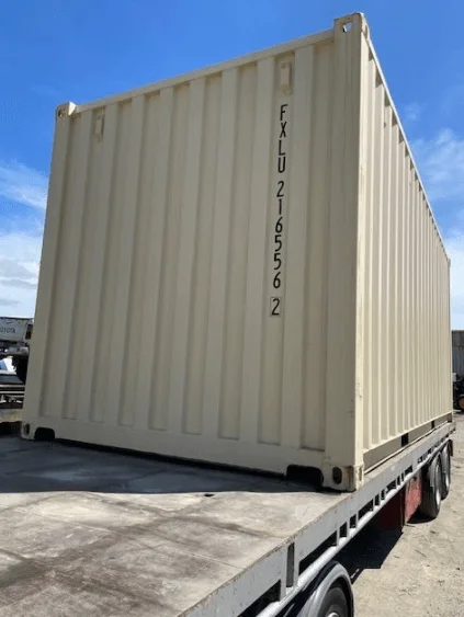 Beige one trip 20ft container loaded on a flatbed trailer under a blue sky