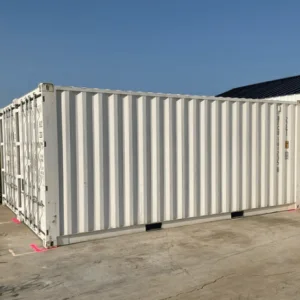 Cream 20ft container parked on concrete beside a farm building