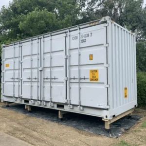 White open side container standing on timber bearers with its side doors closed