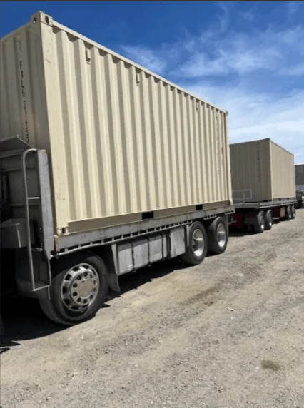 Beige 20ft container on a trailer with a second container waiting behind