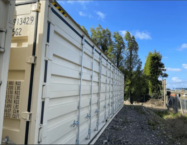 Side doors and locking gear along a beige 40ft container with trees behind