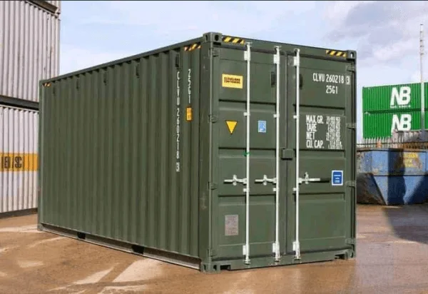 One trip green 20ft container on wet tarmac, showing its side wall and closed cargo doors