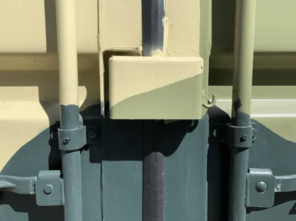 Lockbox welded between the door handles of a camouflage painted container