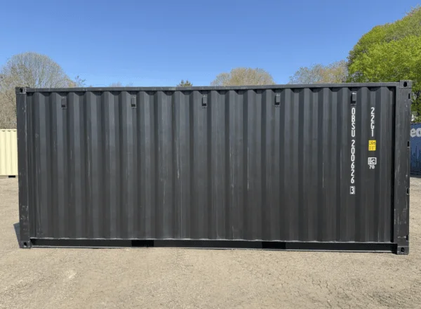 Side elevation of a matte black 20ft storage container under a clear blue sky