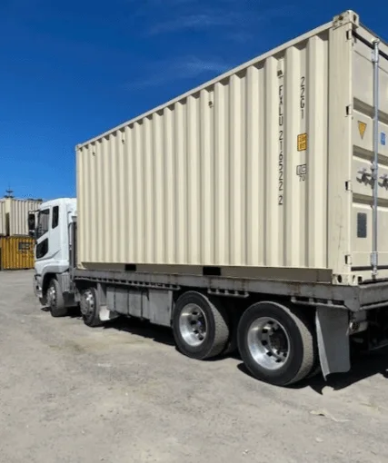 Beige 20ft container riding on the back of a delivery truck