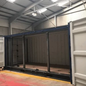 Dark grey open side container in a workshop with the side frame exposed
