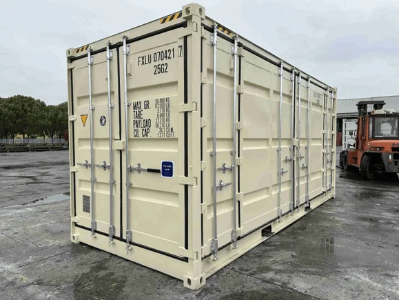 Beige open side container with its side doors closed, parked on wet concrete