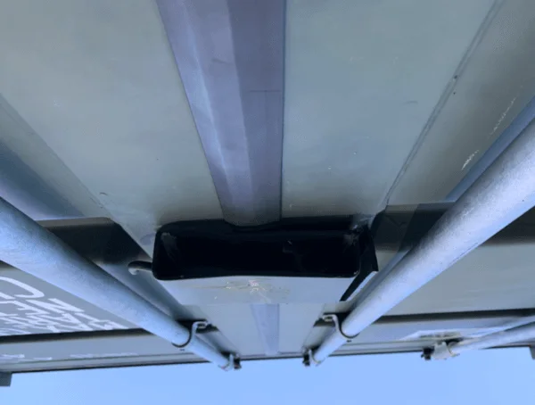 Looking up at the door header and locking bar hardware under the roof edge of a container