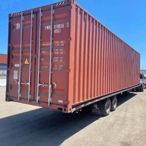 Red 40ft high cube container loaded on a trailer at a container depot