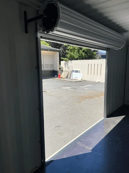 Roller shutter rolled up onto its drum above the opening in a container side