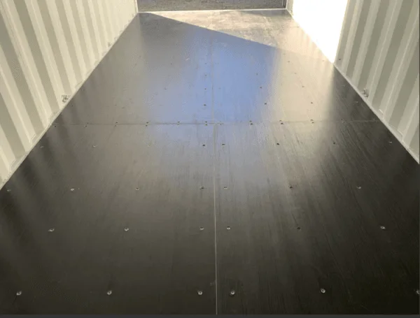 Sunlight falling across the dark timber floor inside a 20ft container
