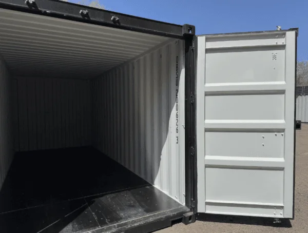 Both doors open on a black 20ft container, with sunlight falling across the floor