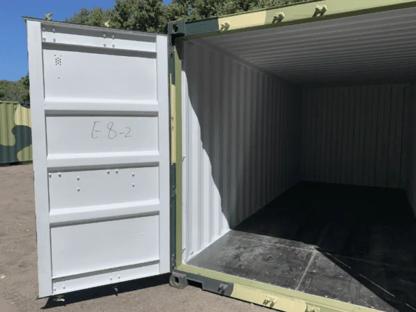 One door open on a camouflage container showing the pale interior and dark floor