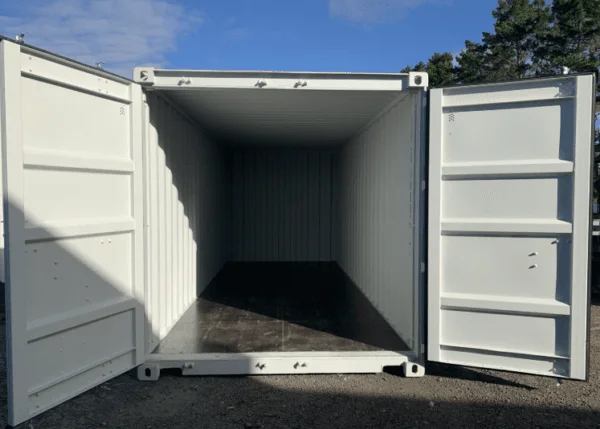 Doors open on a light grey 20ft container under a blue sky with trees behind