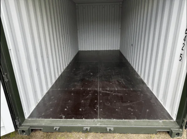 Dark painted floor of a green 20ft container seen from the open doorway