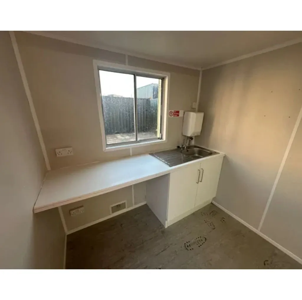 Kitchenette with a stainless sink, worktop and water heater below a sliding window