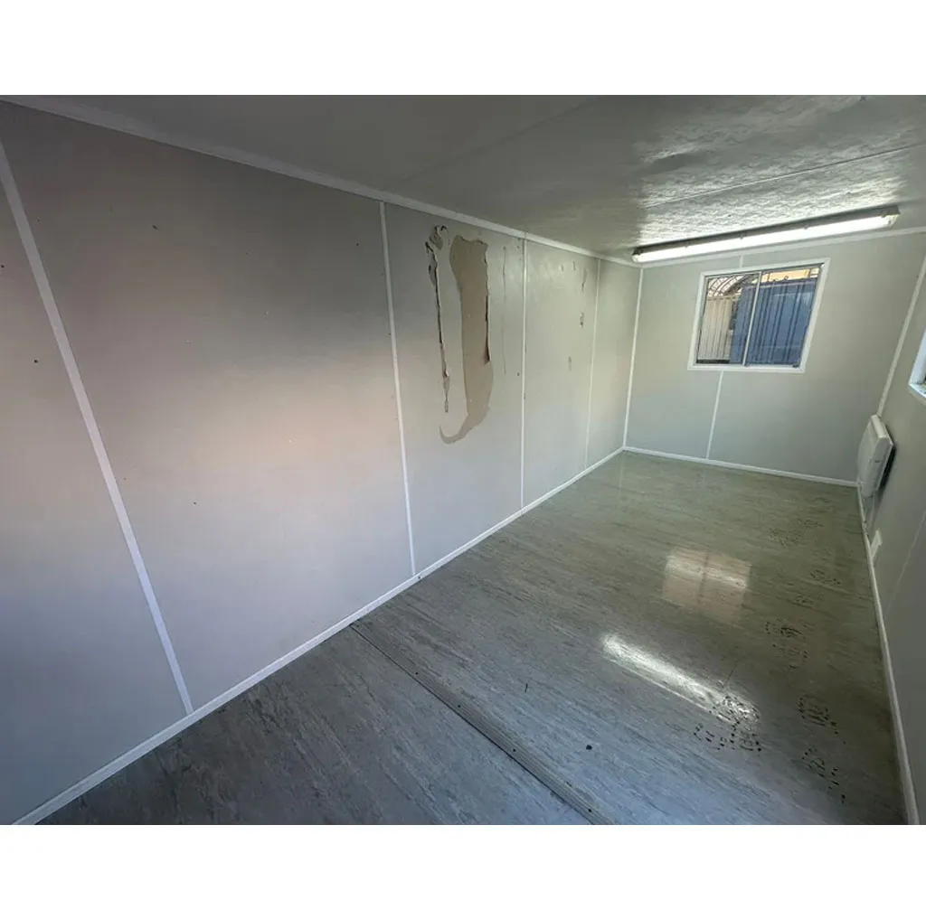 Bare interior of a container office cabin with a window and ceiling strip light
