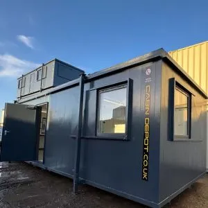 Dark grey anti-vandal cabin with its door open, stacked beside other cabins