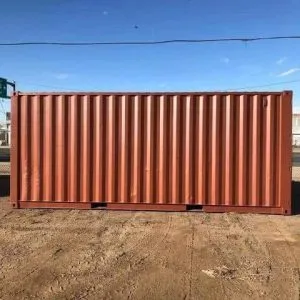 Side elevation of a rust coloured used 20ft container standing on bare ground