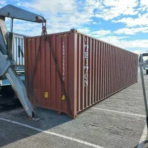 Truck mounted sideloader crane lifting a brown 40ft container by its corners