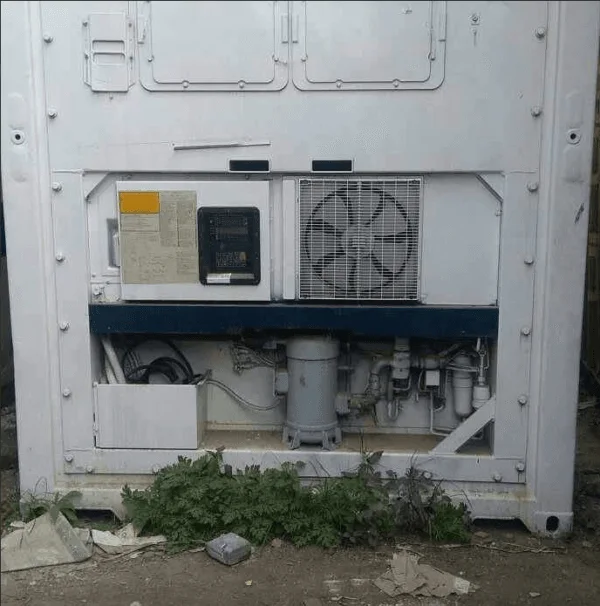 Older refrigeration unit with exposed fan and pipework on a reefer container