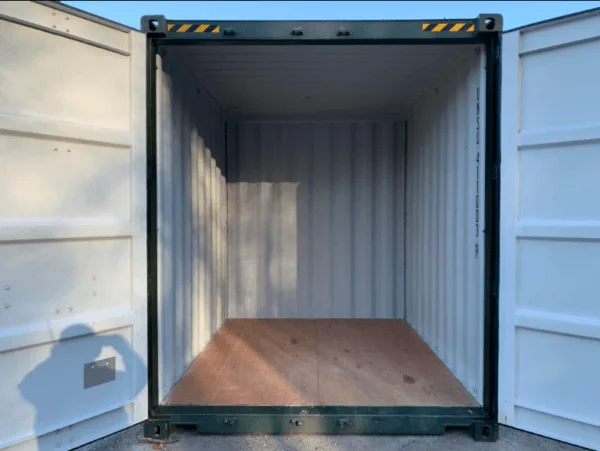 Both doors open on a green 10ft container, showing white walls and a plywood floor